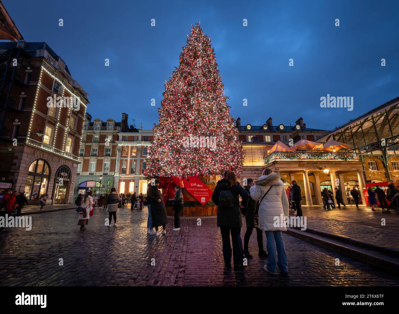 London, UK - 8. November 2023: Großer, geschmückter Weihnachtsbaum vor dem Covent Garden Market. Die Leute bewundern die Lichter auf dem Baum. Querformat. Stockfoto