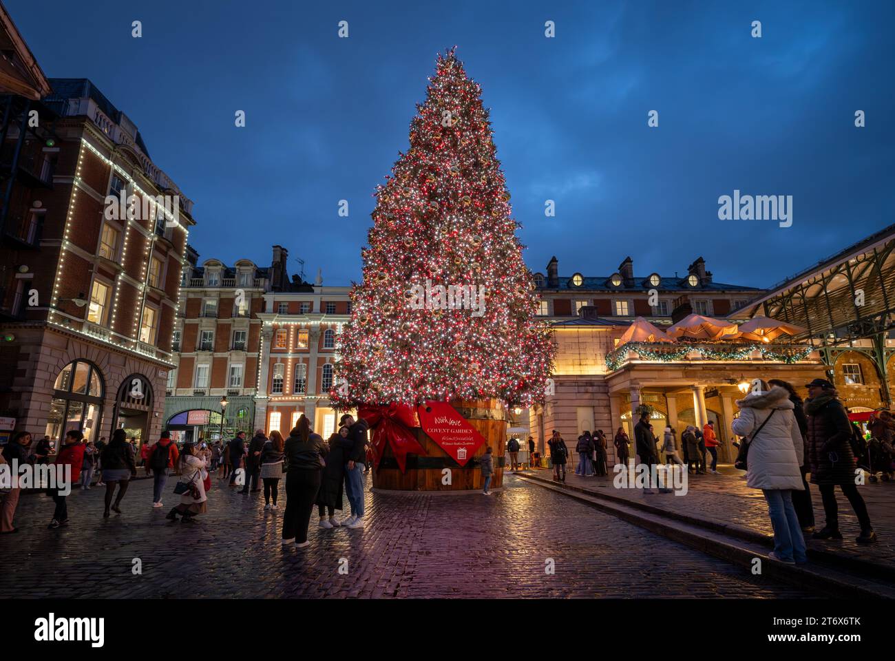 London, UK - 8. November 2023: Großer, geschmückter Weihnachtsbaum vor dem Covent Garden Market. Die Leute bewundern die Lichter auf dem Baum. Querformat. Stockfoto