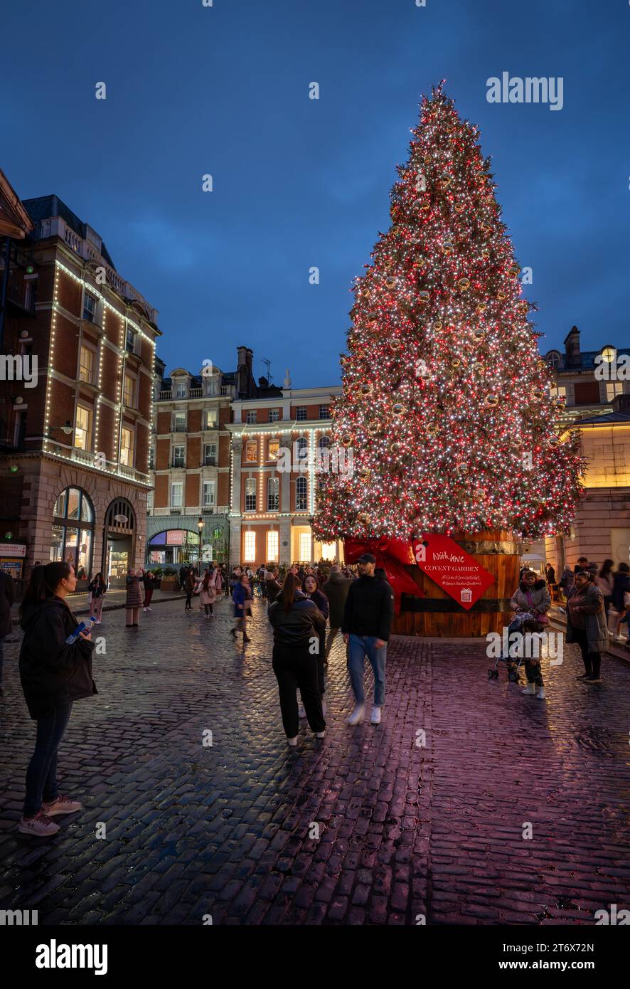 London, Großbritannien - 8. November 2023: Großer, geschmückter Weihnachtsbaum vor dem Covent Garden Market mit Leuten auf der Straße. Hochformat. Stockfoto