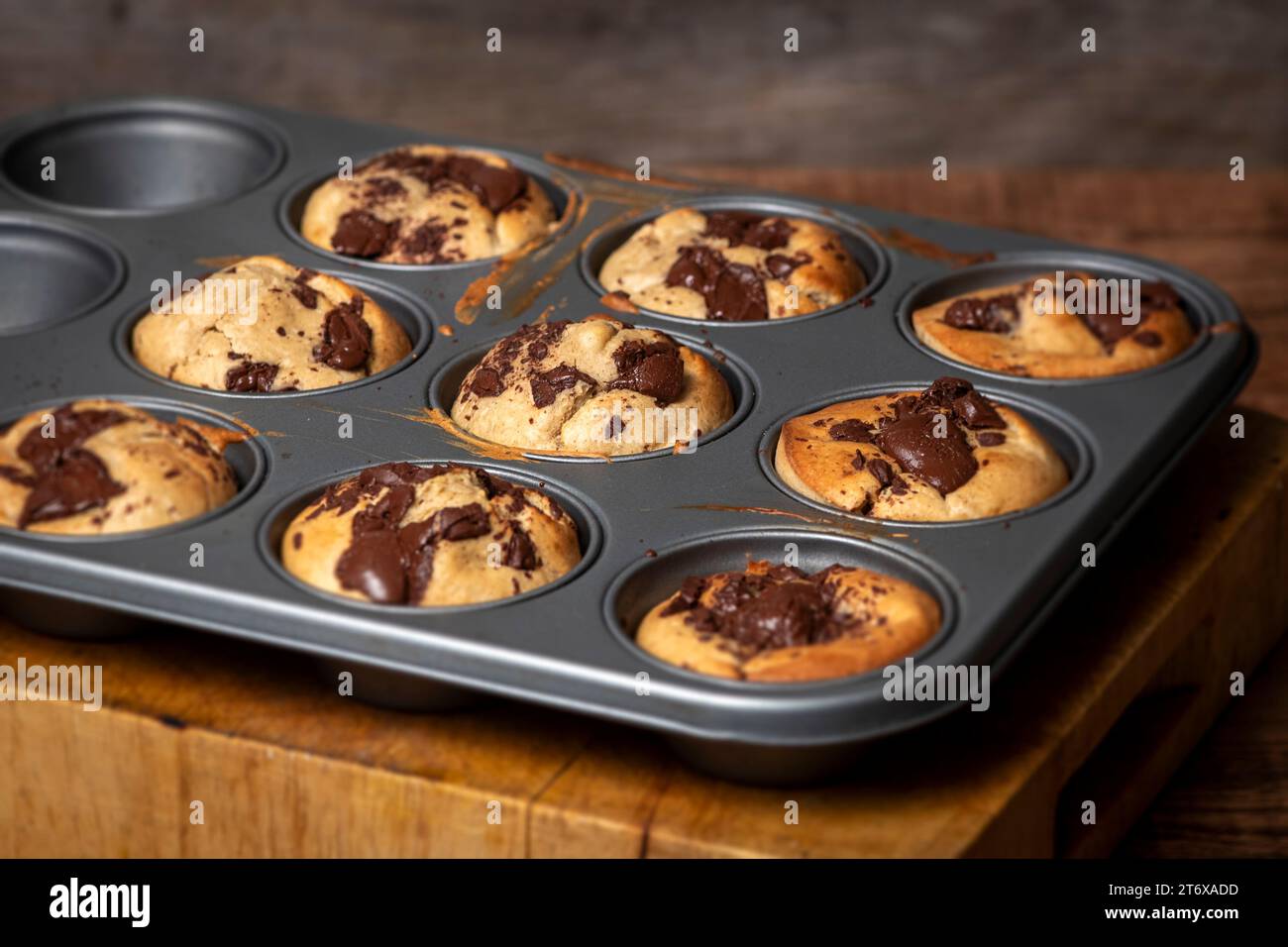 Hausgemachte Bananen- und Schokoladenmuffins aus dem Ofen in einem Blech mit schmelzender Schokolade. Stockfoto