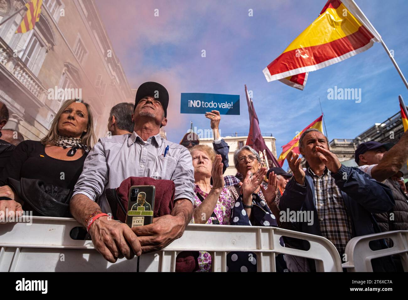 Unter Plakaten und Fahnen ist ein Demonstrant mit einem Telefonetui zu sehen, in dem er um die Wahl des Vorsitzenden der ultraspanischen Partei VOX während der Demonstration bittet. Tausende von spanischen Gewerkschaftern haben sich auf der Plaza de Sant Jaume gegen die Amnestie katalanischer politischer Vertreter und gegen die Einführungsvereinbarungen des amtierenden Präsidenten Pedro Sánchez und der nationalistischen politischen Kräfte Kataloniens versammelt. (Foto: Paco Freire / SOPA Images/SIPA USA) Stockfoto