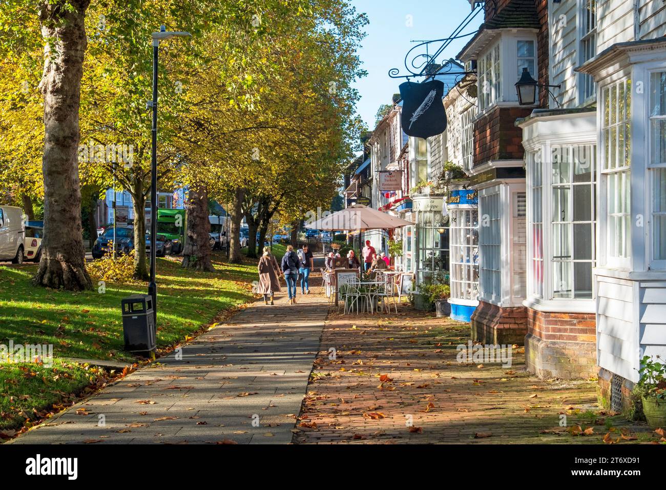 Tenterden High Street, von Bäumen gesäumte Straße, breiter Bürgersteig mit Geschäften und Cafés, an einem sonnigen Herbsttag, Kent, Großbritannien Stockfoto