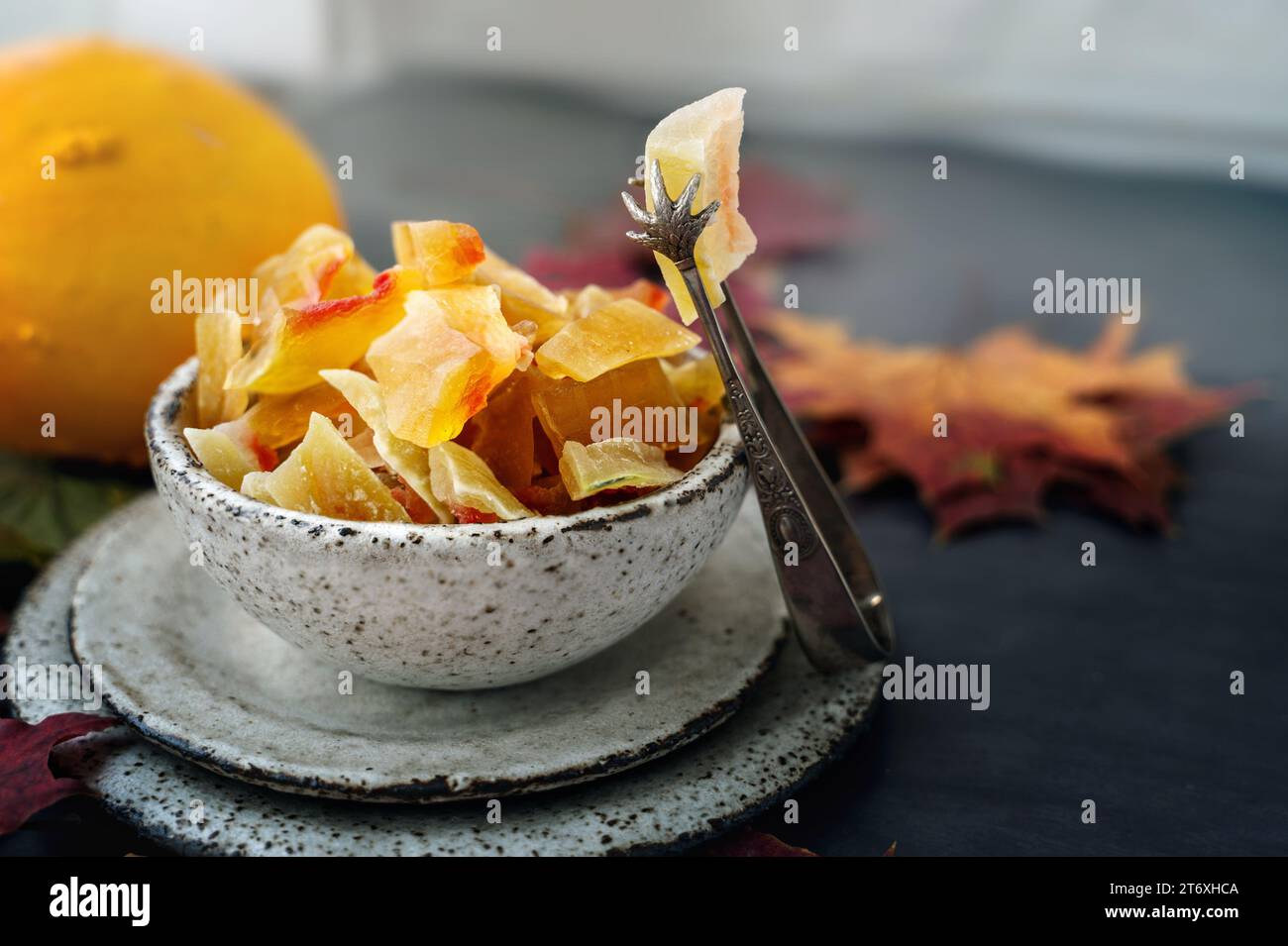 Kandierter und getrockneter Kürbis. Nahaufnahme von kandierten Früchten von hausgemachtem Kürbis aus einer natürlichen Farm, bestreut mit Puderzucker in handgemachtem Steingut. Stockfoto