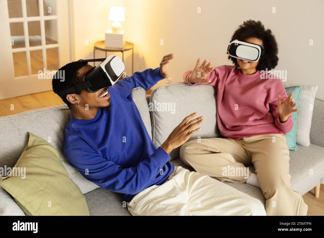 Schwarzes Paar mit VR-Brille, die in die Augmented Reality Indoor eintauchen Stockfoto