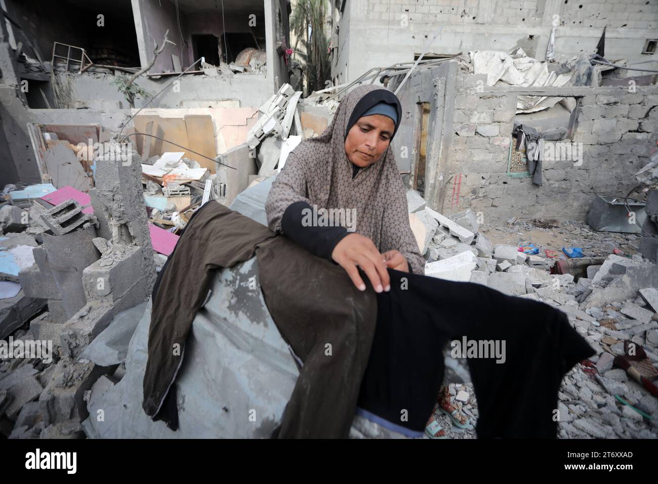 Rafah, Gaza. November 2023. Amal al-Robayaa 44, verbreitete die Kleidung in den Ruinen des Familienhauses, das bei einem israelischen Streik in Rafah im südlichen Gazastreifen am Sonntag, den 7. November 2023 zerstört wurde. Robayaa sagt, dass der Wohnblock, in dem er lebte, am 7. Oktober, dem ersten Tag des Krieges in Gaza, durch einen israelischen Bombardement zerstört wurde. Amal Rabayaa, Ehemann von Imad, versickert nun mit anderen Familienmitgliedern in einer UN-Schule in Rafah, kehrt aber am Morgen in ihr Zuhause zurück und stellt sich dem täglichen Kampf um Nahrung und Wasser. Foto: Ismael Mohamad/UPI Credit: UPI/Alamy Live News Stockfoto