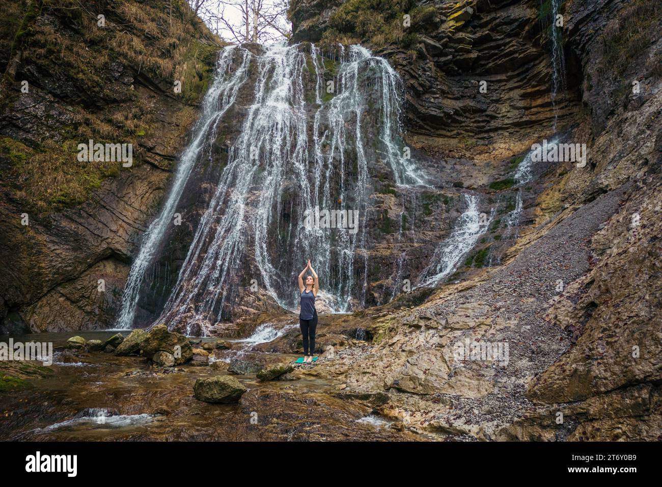 Fitte junge Frau, die Yoga in einer wunderschönen Landschaft mit Wasserfällen praktiziert. Konzepte von ganzheitlichem Erleben, Mensch und Naturverbund. Stockfoto