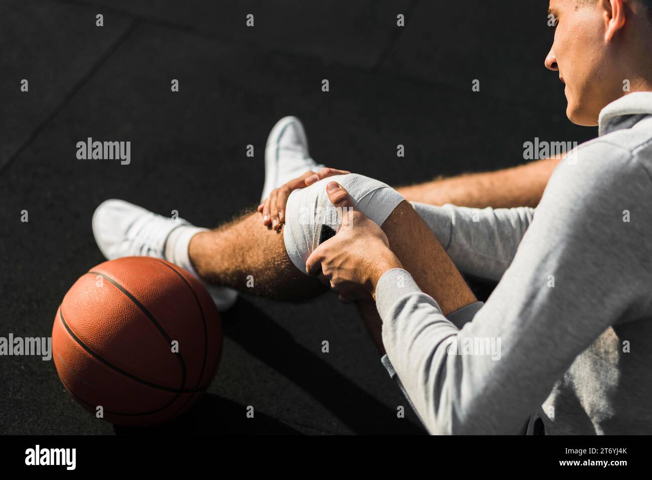 Basketballspieler, der das Knie mit Bandage anlegt Stockfoto