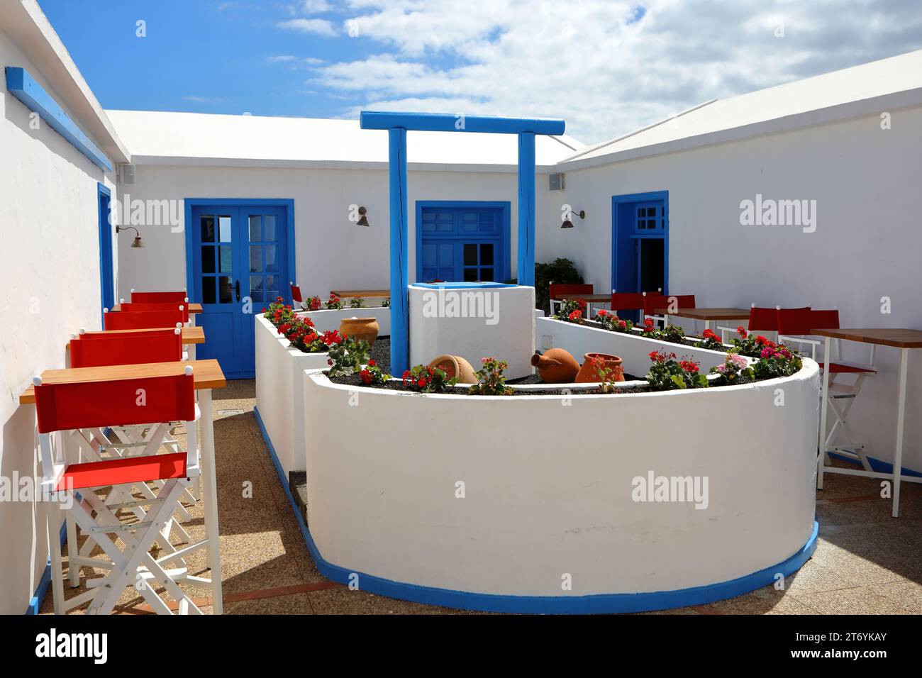 Ein hübscher Essbereich in weiß und Blau um einen alten Brunnen herum Stockfoto