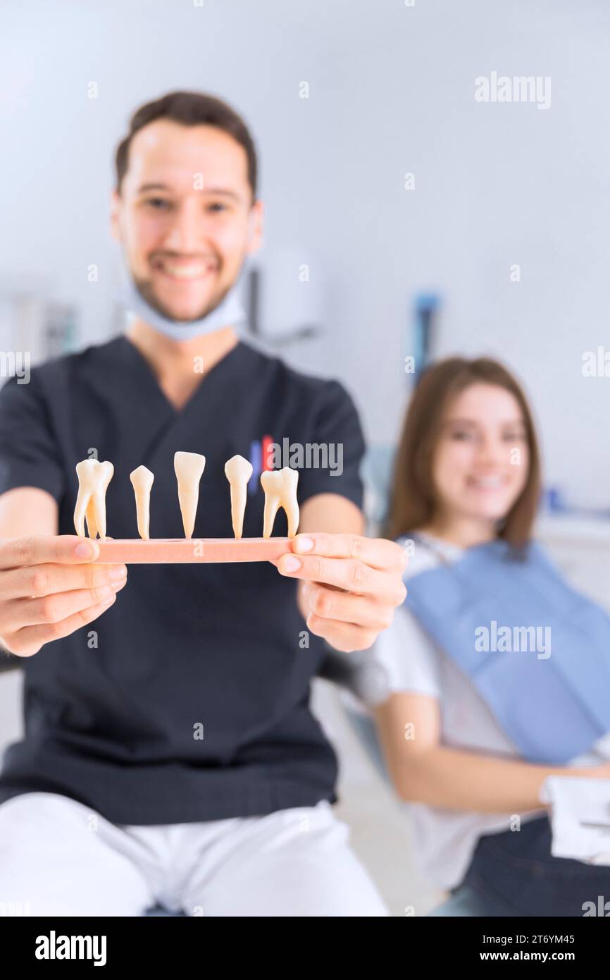 Männlicher Zahnarzt zeigt Zahnmodell sitzend weibliche Patientin Stockfoto