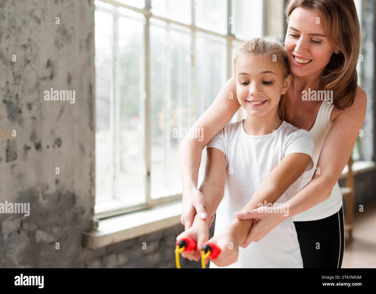 Mutter bringt der Tochter bei, wie man Sprungseil benutzt Stockfoto