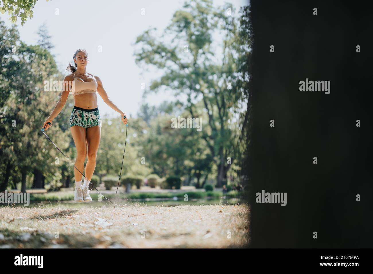 Sportliche Frau führt Freunde in einem Park-Workout. Seilspringen, Stretching und genießen Sie den sonnigen Tag für einen gesunden Lebensstil. Stockfoto