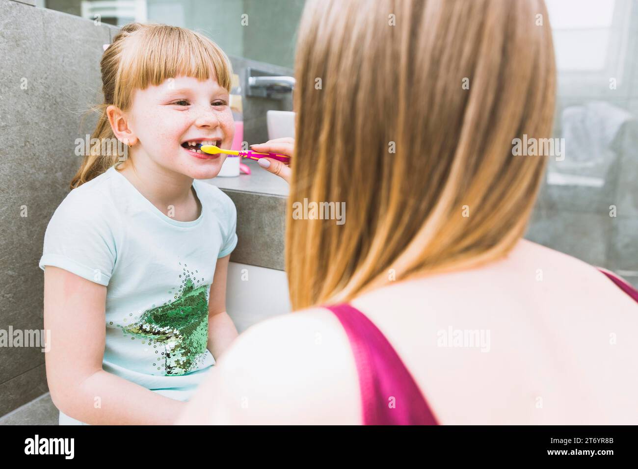 Gesichtslose Mutter, die Zähne putzt, Tochter Stockfoto