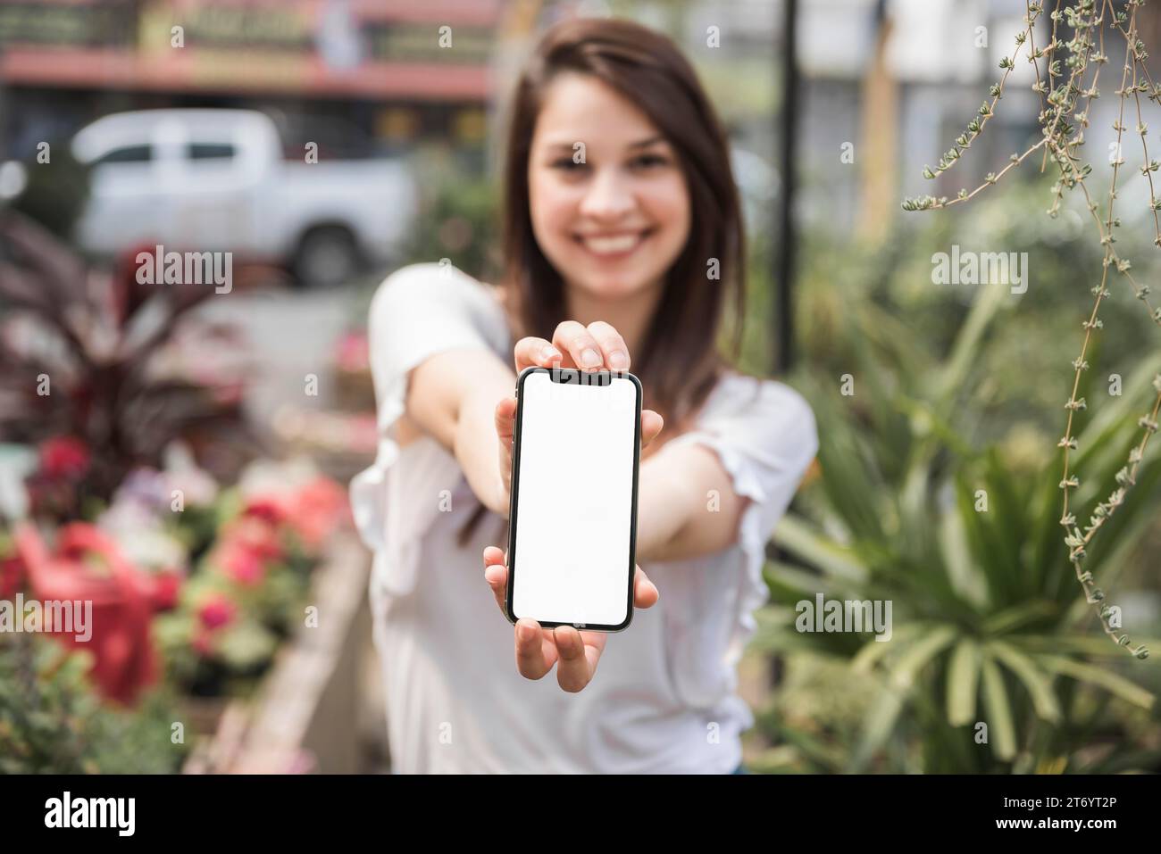 Glückliche Frau zeigt Handy mit leerem weißen Bildschirm Stockfoto