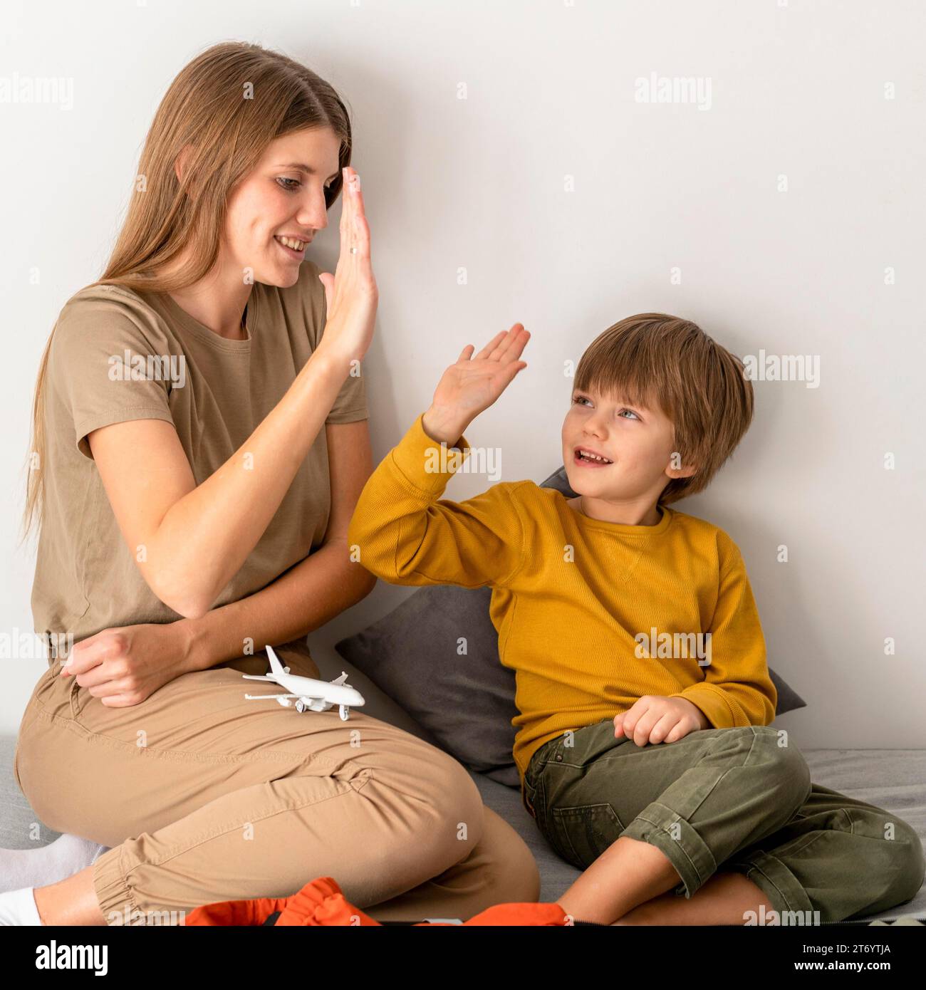 Mutter High Five sich gegenseitig, während sie Gepäckreisen vorbereitet Stockfoto