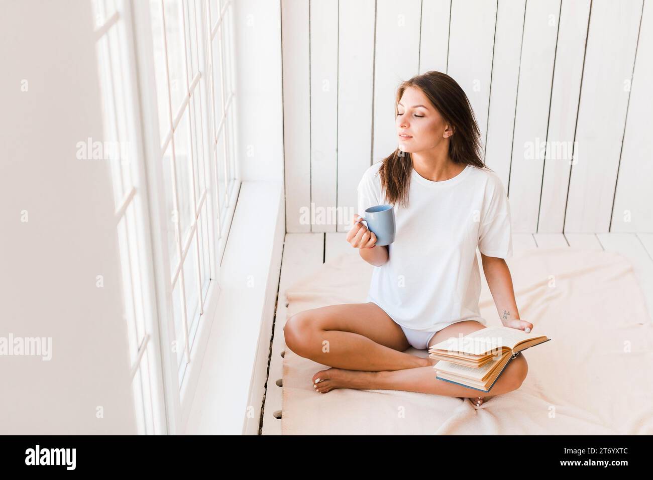 Frau mit Becherbuch, die Sonnenlicht genießt Stockfoto