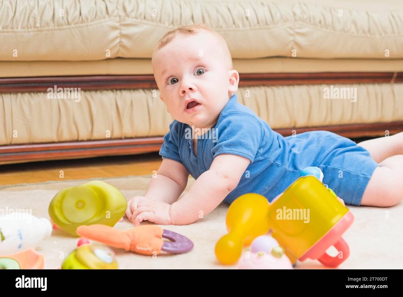 Niedlicher Junge, der Teppich mit Spielzeug legt Stockfoto