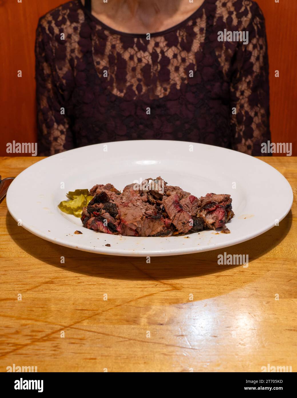 Frau, die an einem Tisch saß, mit einem Teller mit gekochtem Brustfleisch vor sich. Typische Keto-Diät- oder Fleischfresser-Diät-Mahlzeit. Stockfoto