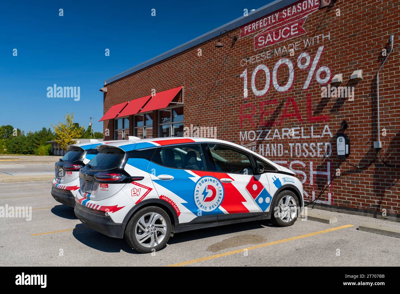 Terre Haute, IN - 30. September 2023: Dominos elektrische Lieferfahrzeuge werden neben ihrem Gebäude aufgeladen. Stockfoto