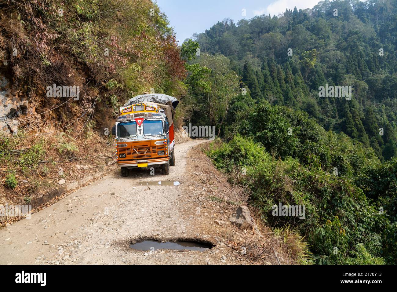 Lastwagen beladen mit Gütern, die entlang einer gefährlichen Bergstraße mit Schlaglöchern in der Nähe von Kolakham im Bezirk Kalimpong, Indien, fahren. Stockfoto