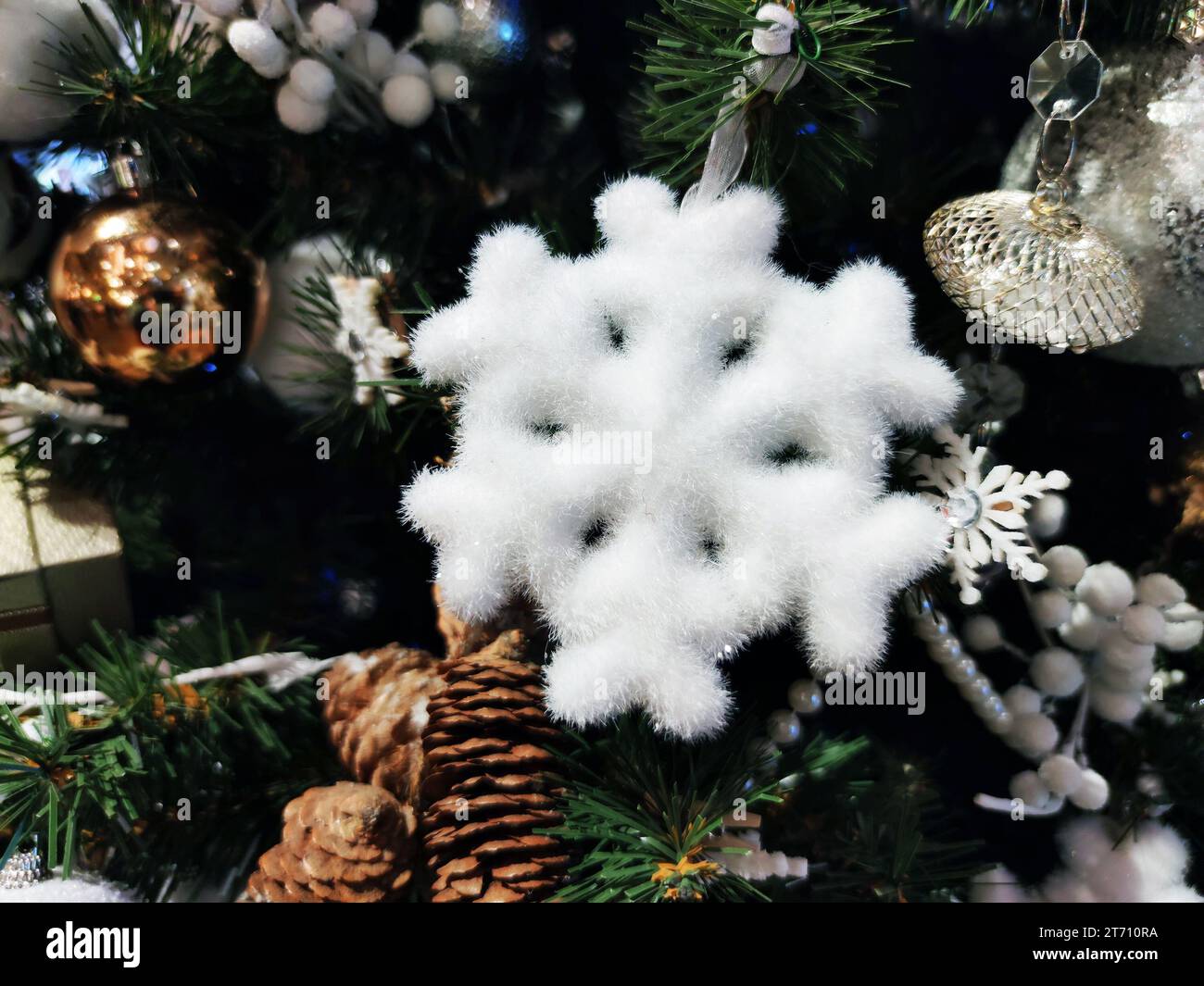 Weiße Schneeflocken schmücken den Weihnachtsbaum in Nahaufnahme. Stockfoto