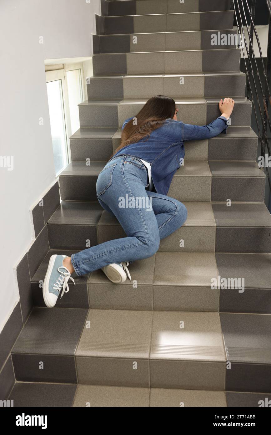 Bewusstlose Frau, die auf einer Treppe liegt, nachdem sie drinnen gefallen ist Stockfoto