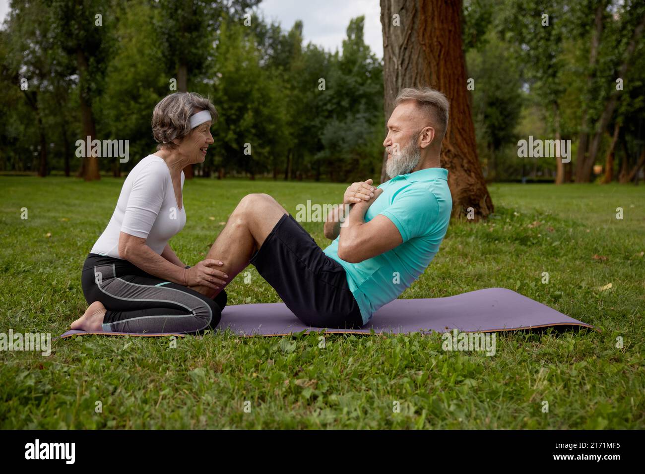 Glückliche verheiratete Rentner, die im Park trainieren Stockfoto