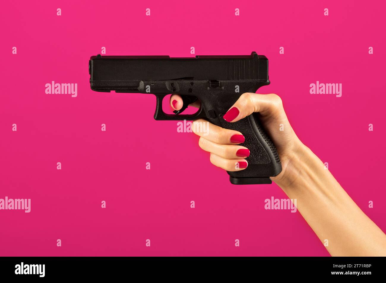 Anonyme schlanke Frau mit Nägeln polierte Hand, Zeigefinger auf Abzug und Handfläche auf Handfeuergriff, demonstrierend vor rosa Hintergrund Stockfoto