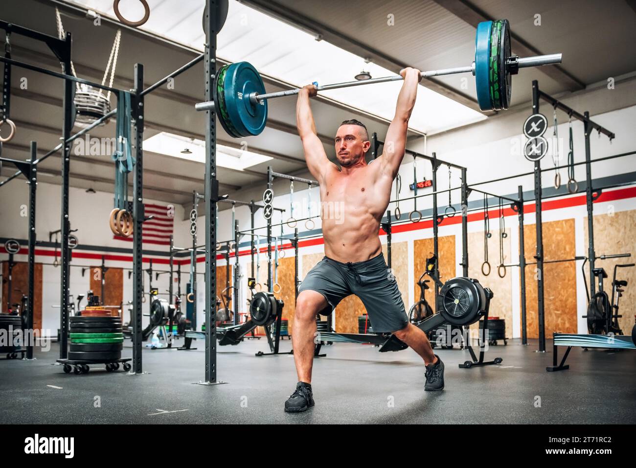 Ganzkörper eines starken männlichen Athleten, der während des Gewichtheben-Trainings im Fitnessstudio saubere und ruckartige Übungen durchführt Stockfoto