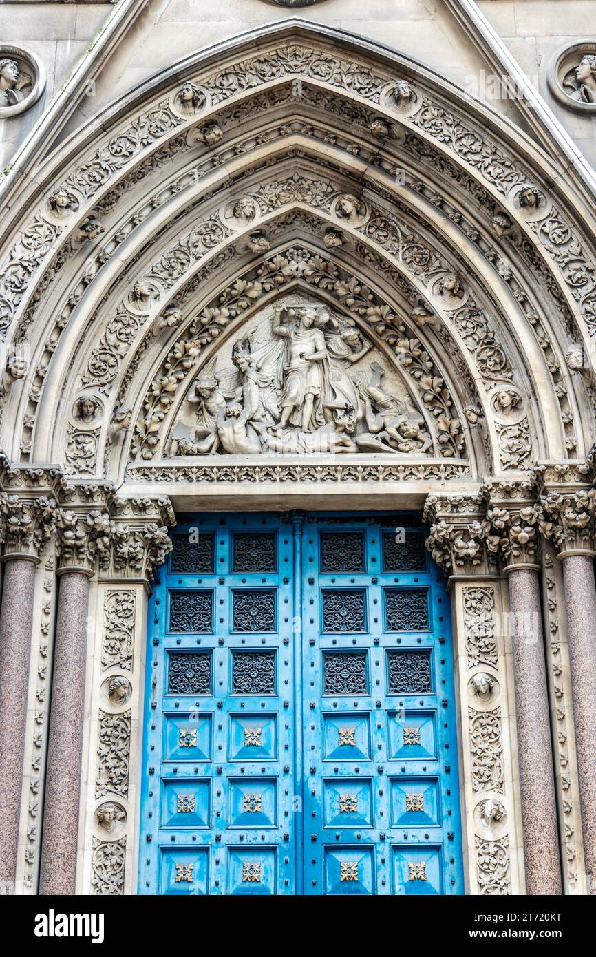 Archivolt- und Tympanenskulptur „St Michael Disuting with Satan“ der St. Michael's Church in der historischen Square Mile, City of London, England Stockfoto