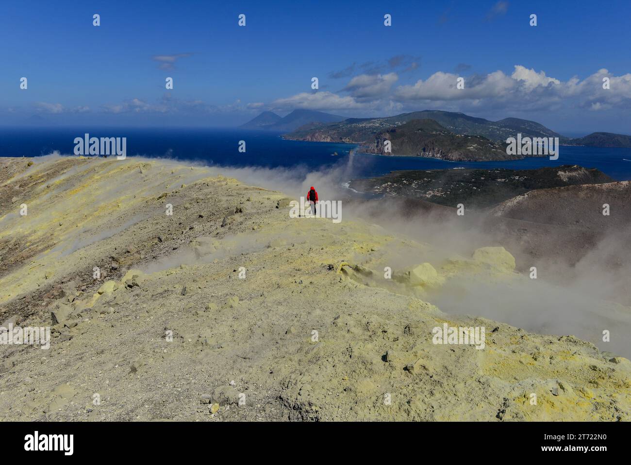 Trekking in Rot inmitten schwefelhaltiger vulkanischer Gase, die aus gelben Fumarolen um den riesigen Krater Vulcano, Äolische Inseln, Italien, austreten Stockfoto