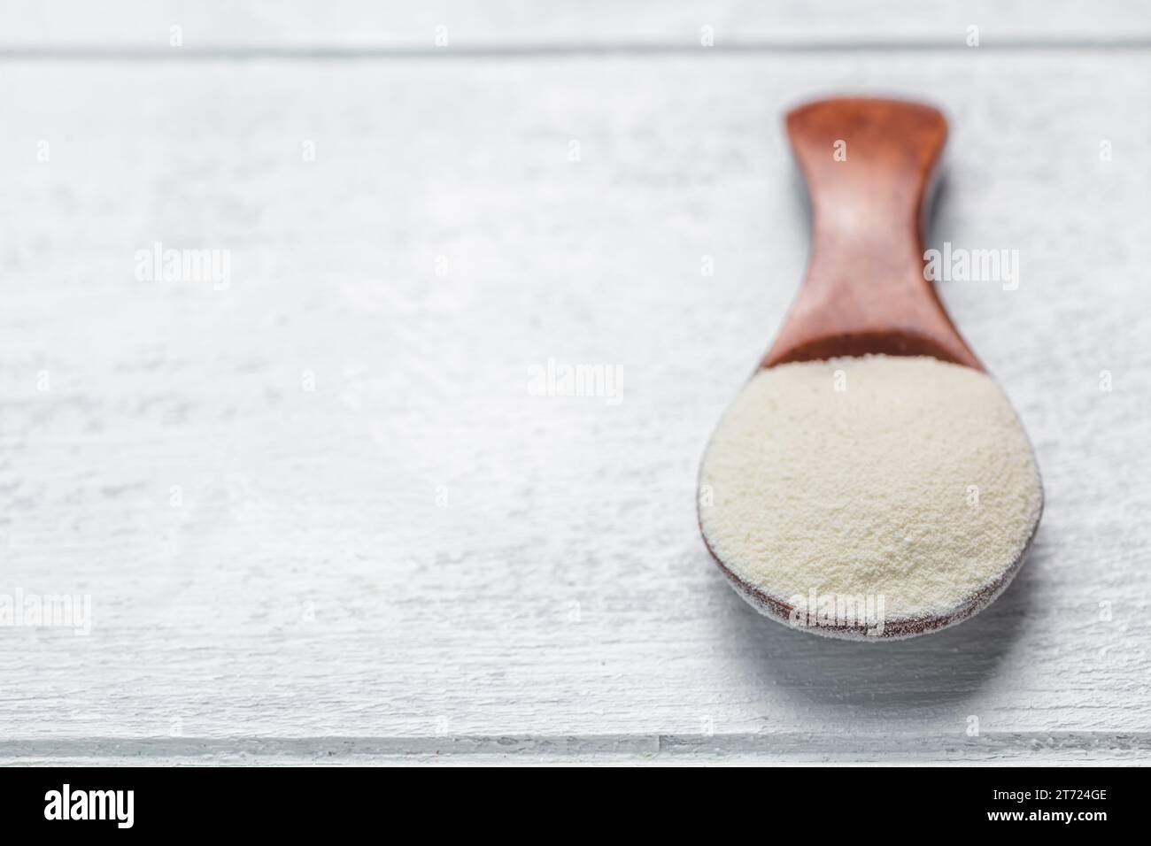 Kollagenpulver im Löffel auf weißem Hintergrund aus Holz. Zusätzliche Proteinaufnahme. Natürliche Schönheit und Gesundheit zu ergänzen. Flach liegend, Draufsicht Stockfoto