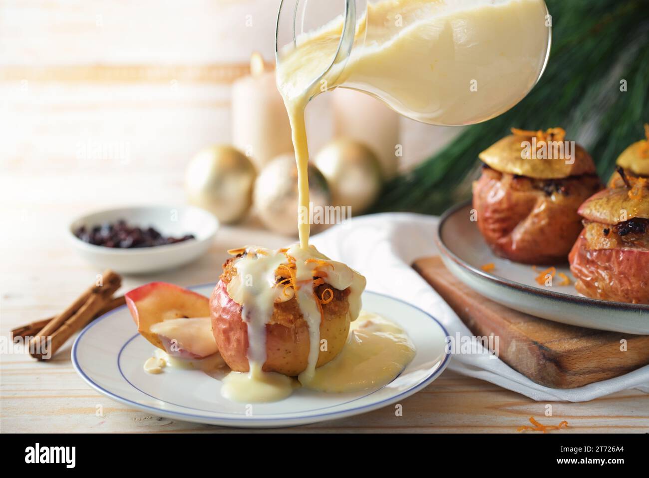 Mit Vanillesauce auf einen gebackenen Apfel gefüllt mit Mandeln, Honig und Rosinen, hausgemachtem Winterdessert für Feiertage wie Weihnachten, Thanksgiving oder ne Stockfoto