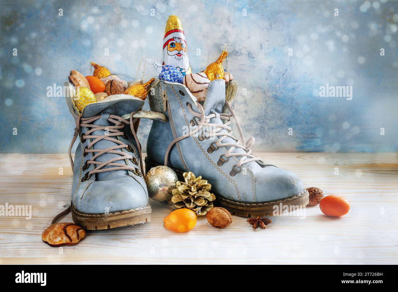 Wanderschuhe gefüllt mit Süßigkeiten, Früchten und Weihnachtsdekoration, Tradition auf Sinterklaas oder in Deutschland Nikolaus Tag am 6. Dezember, hellblauer boke Stockfoto