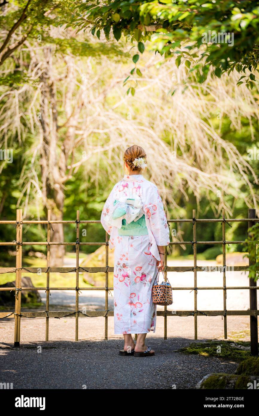 Porträt einer jungen Frau, die Yukata-Sommer-Kimono mit weichem Hintergrund in einem japanischen Garten trägt. Kyoto, Japan. Stockfoto