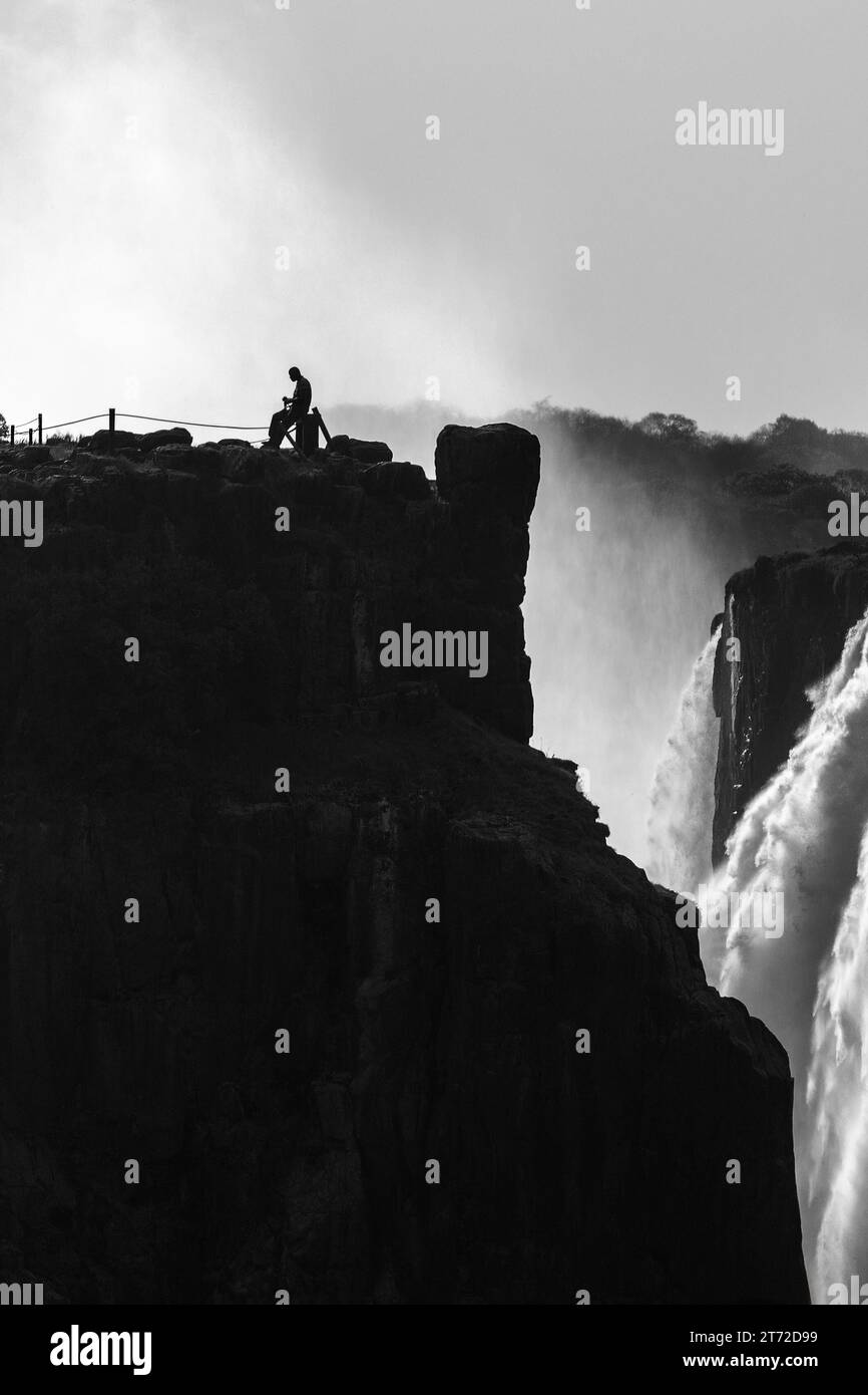 Ein einsamer Grenzwächter auf der simbabwischen Seite der Victoria Falls in Graustufen Stockfoto