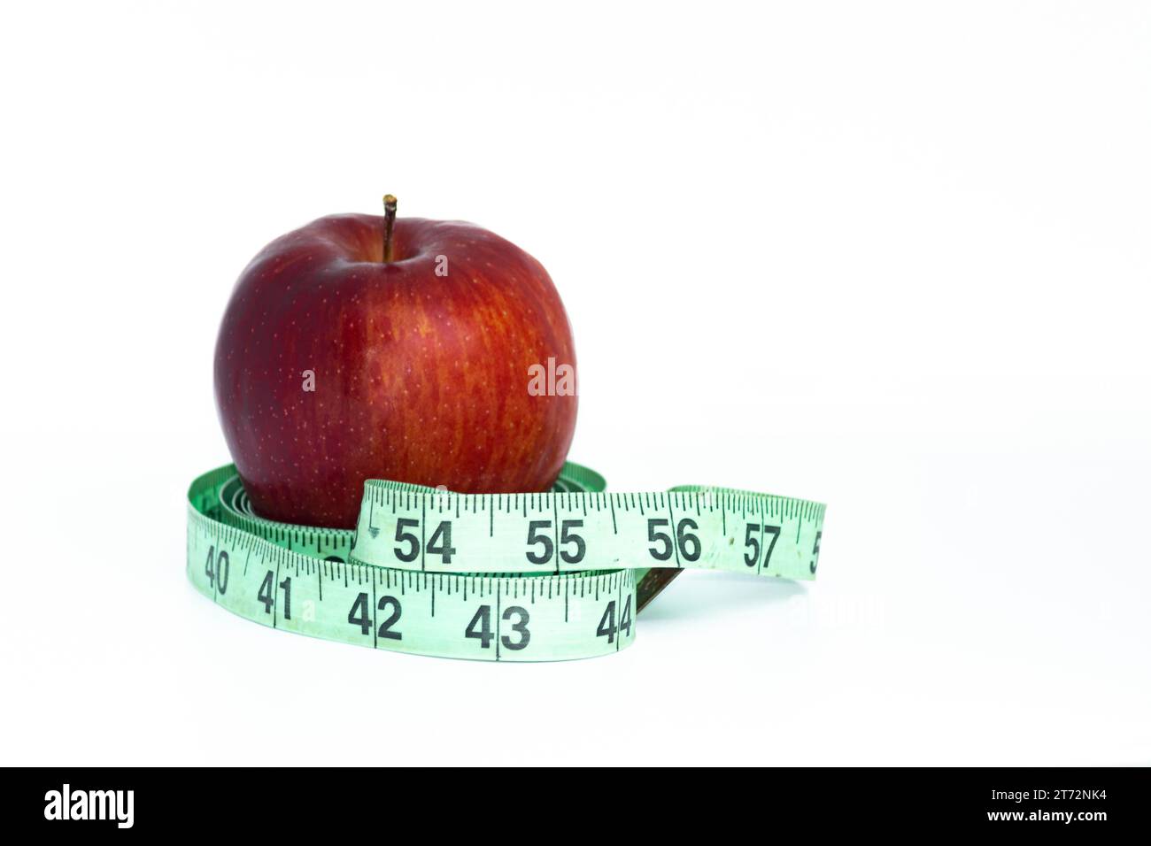 Roter Apfel mit grünem Maßband auf weißem Hintergrund. Gesundheitskonzept. Stockfoto