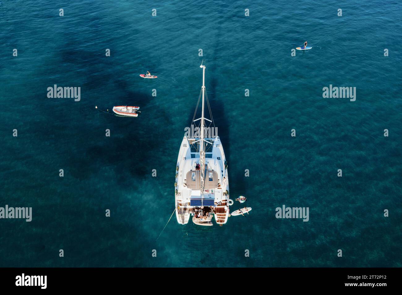 Drohnenblick auf den Katamaran im blauen Meer mit schwimmenden Personen im Sommer. Reisehintergrund. Kreuzfahrturlaub. Stockfoto