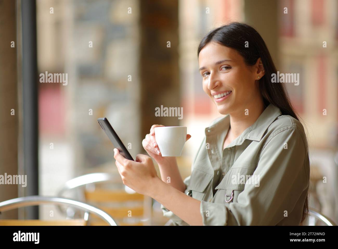 Glückliche Frau beim Frühstück, die einen auf einer Restaurantterrasse ansieht Stockfoto