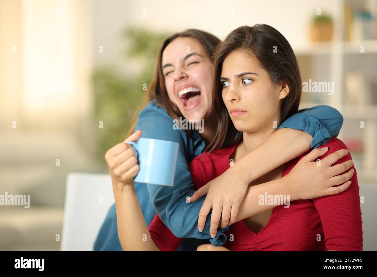 Eine aufgeregte Frau, die zu Hause einen perplexten Freund umschließt Stockfoto