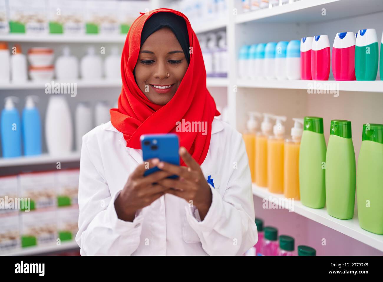 Junge, schöne Apothekerin mit Smartphone, die in der Apotheke arbeitet Stockfoto