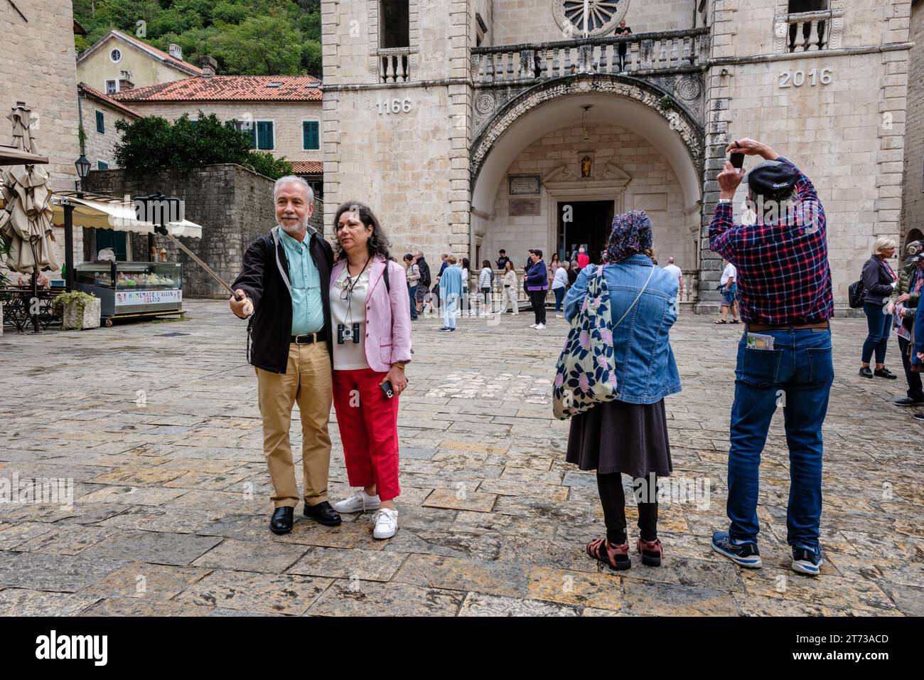 Touristen fotografieren auf dem Tryphon-Platz vor der Kathedrale von St. Tryphon, Kotor, Montenegro Stockfoto
