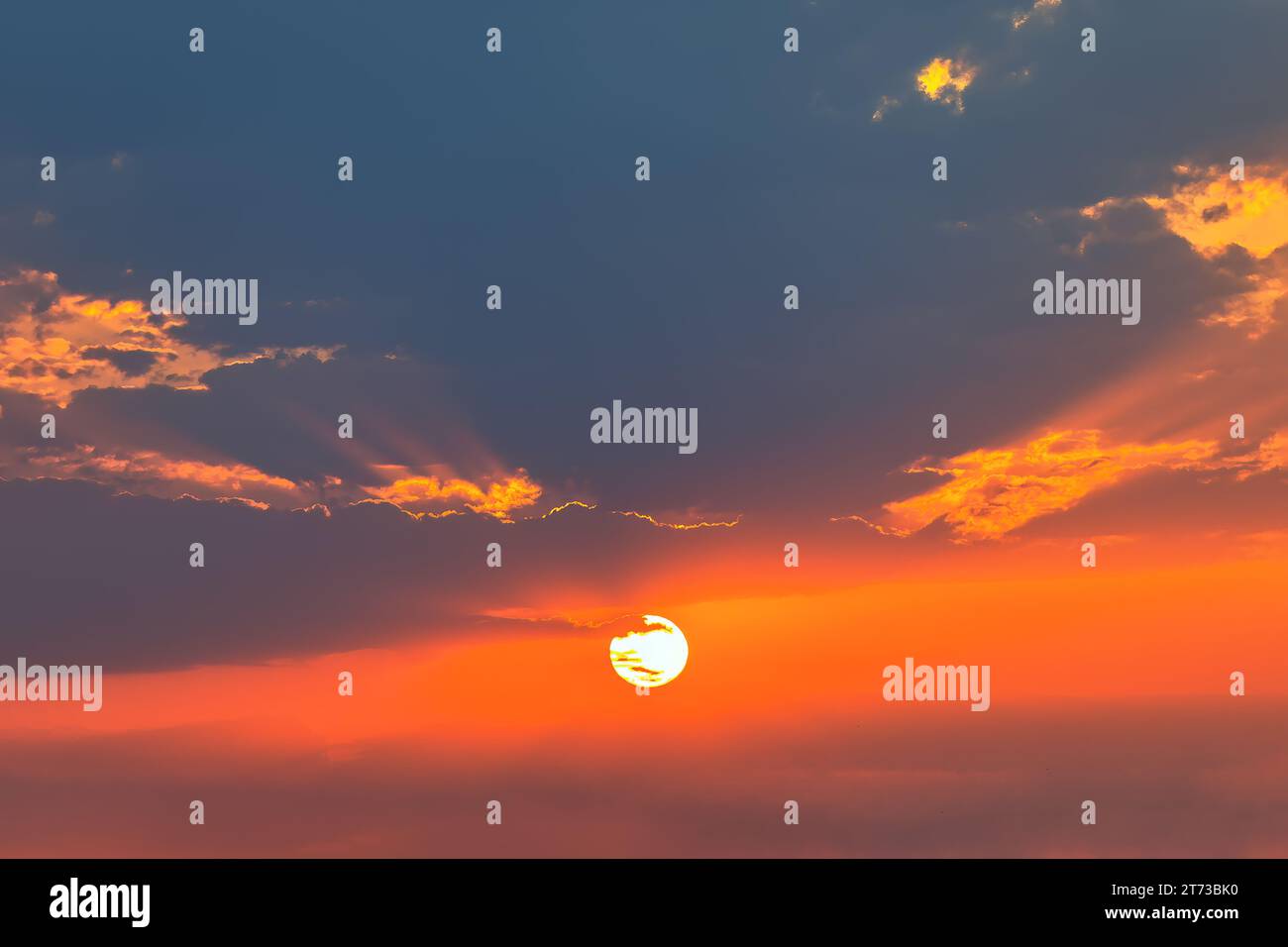 Sonnenuntergangshimmel mit Wolke und Sonnenstrahl, Sonnenuntergangshimmel Hintergrund. Schroffe Wolken, berührt von dem schwindenden Sonnenlicht Stockfoto