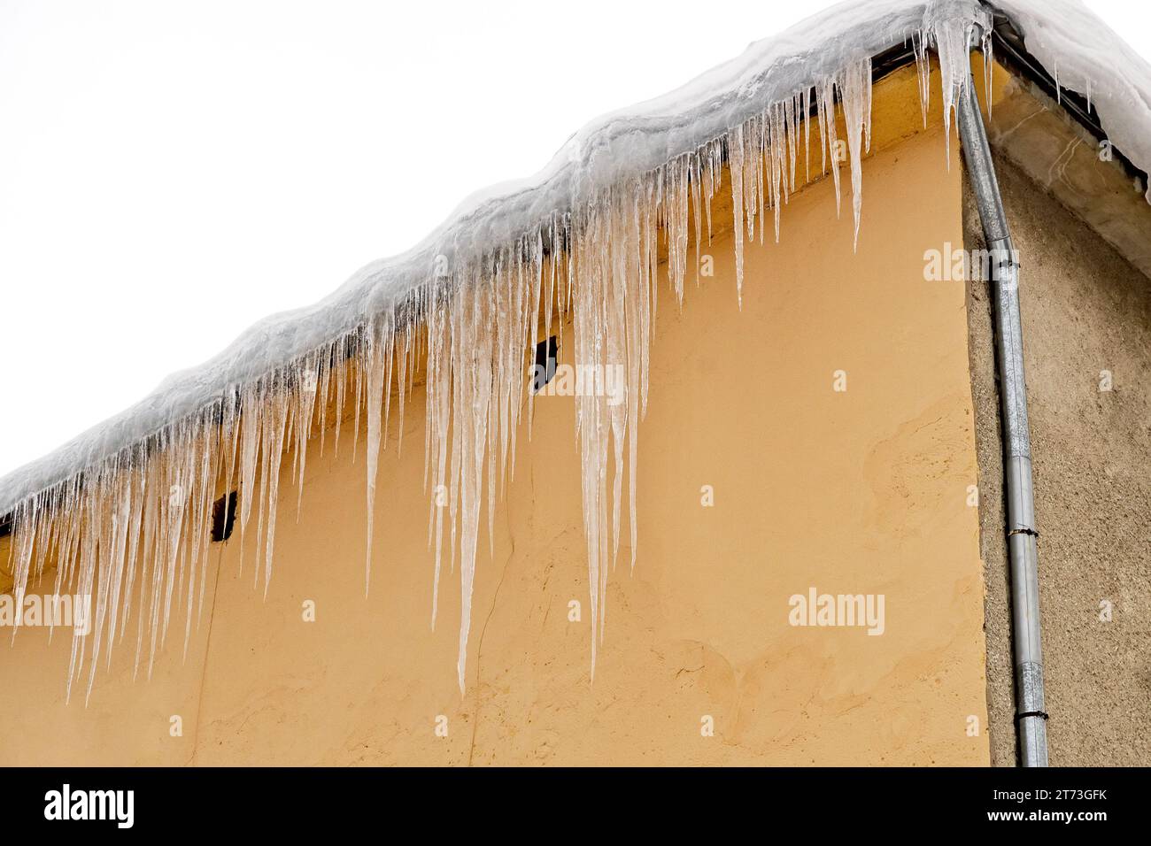 Riesige Eiszapfen hängen an den Traufen von Gebäuden und drohen während des Auftauens einzustürzen Stockfoto