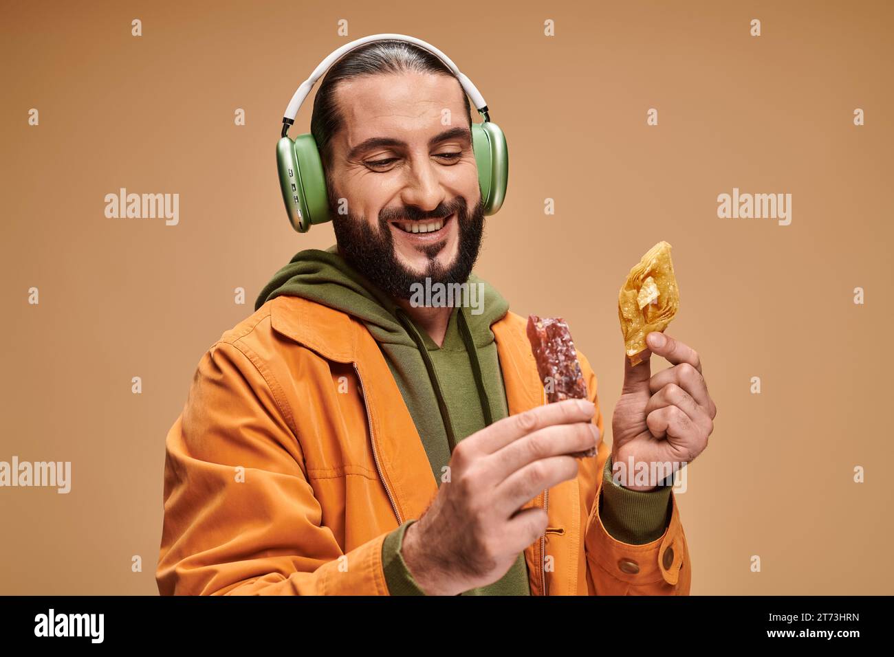Glücklicher Mann in Kopfhörern mit zwei Desserts aus dem Nahen Osten, Honigbaklava und Kirchchchela Stockfoto