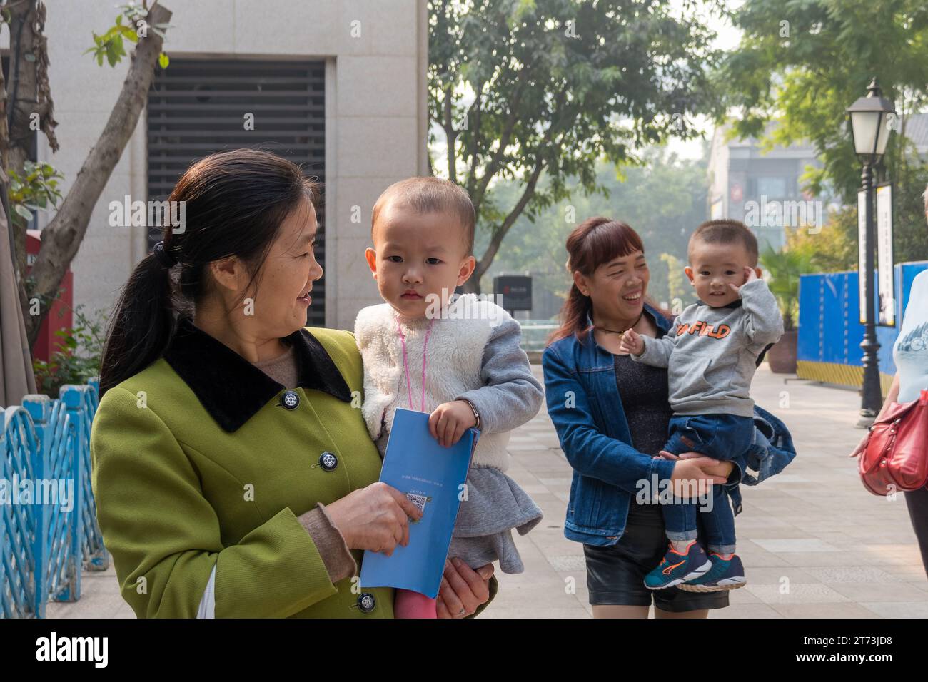 Zwei chinesische Großmütter halten ihr kleines Kind fest. Stockfoto