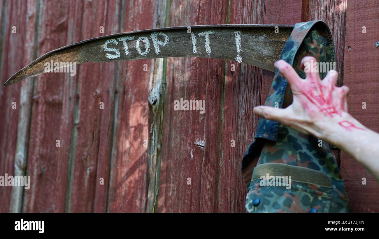 Rosty Sense, HÖR AUF, ES drauf zu schreiben. Eine Hand mit KRIEG in Rot, die an einer Militärjacke greift. Stockfoto