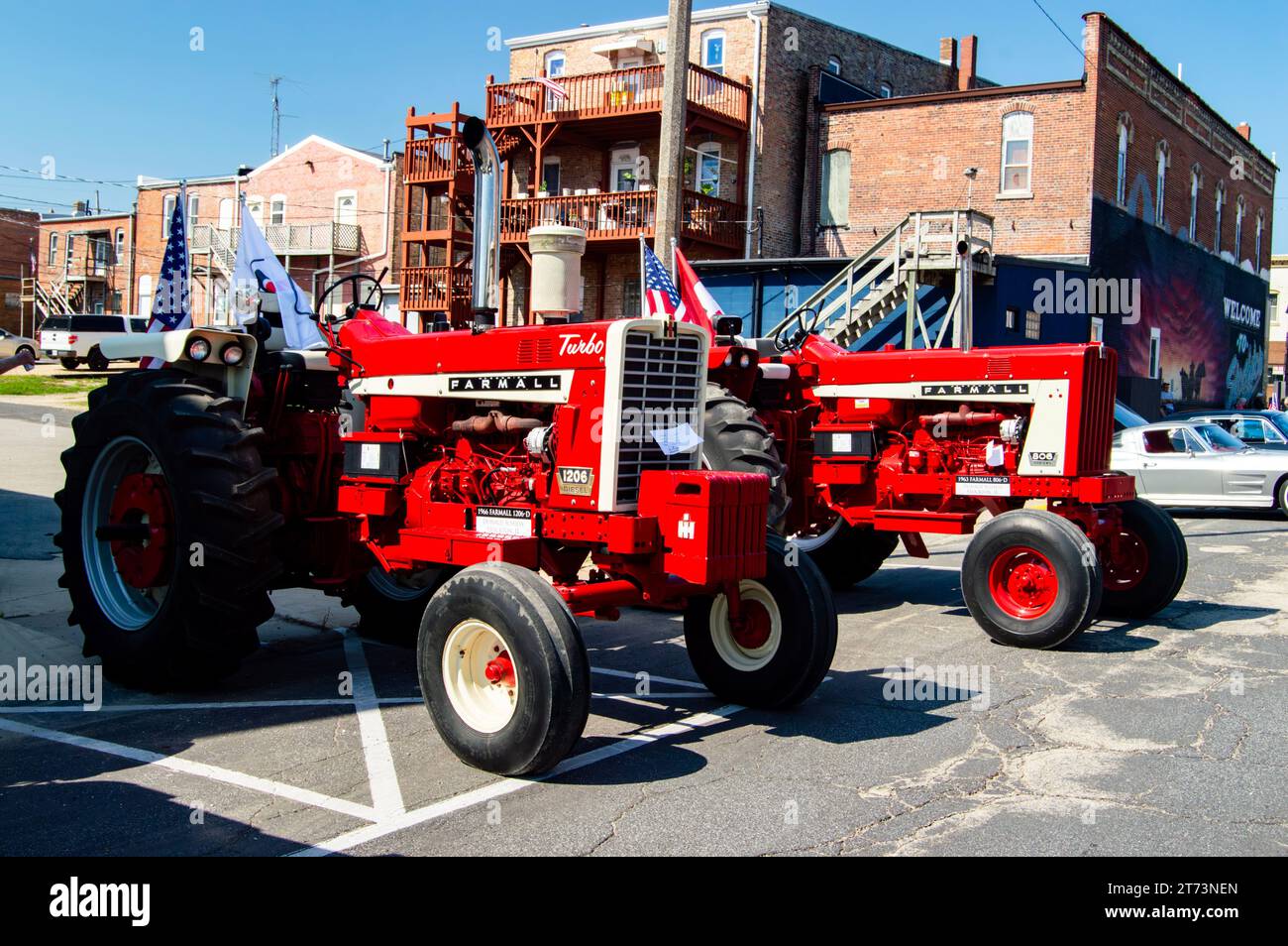 Ein Bild eines roten Traktors, der vor einem großen Gebäude auf einer Stadtstraße parkt Stockfoto