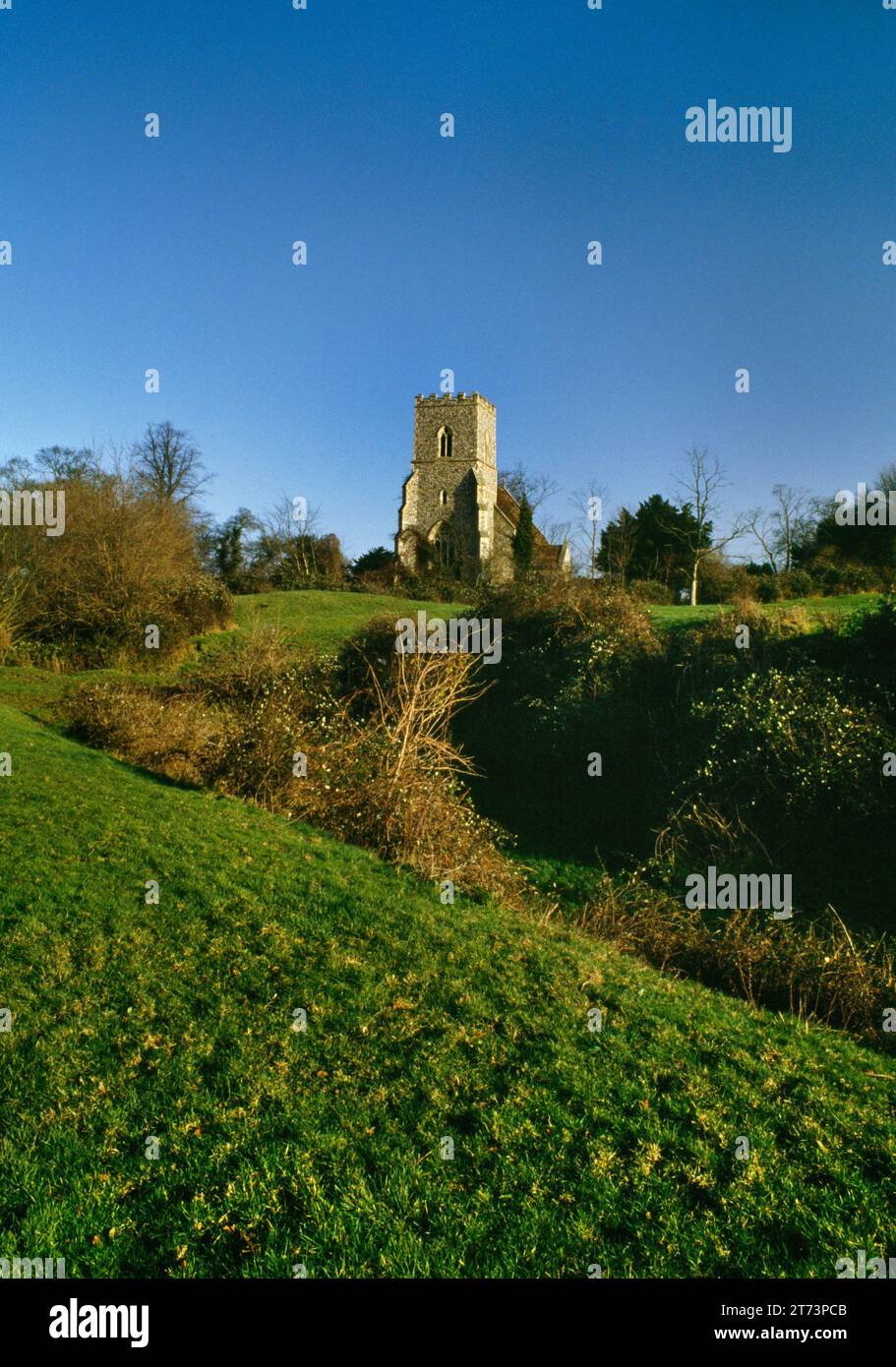 Sehen Sie nordöstlich von All Saints, hauptsächlich die Kirche aus dem 15. Jahrhundert, die sich in den Erdwerken von Castle Camps Norman Motte & Bailey Castle befindet, Cambridgeshire, England, Großbritannien. Stockfoto
