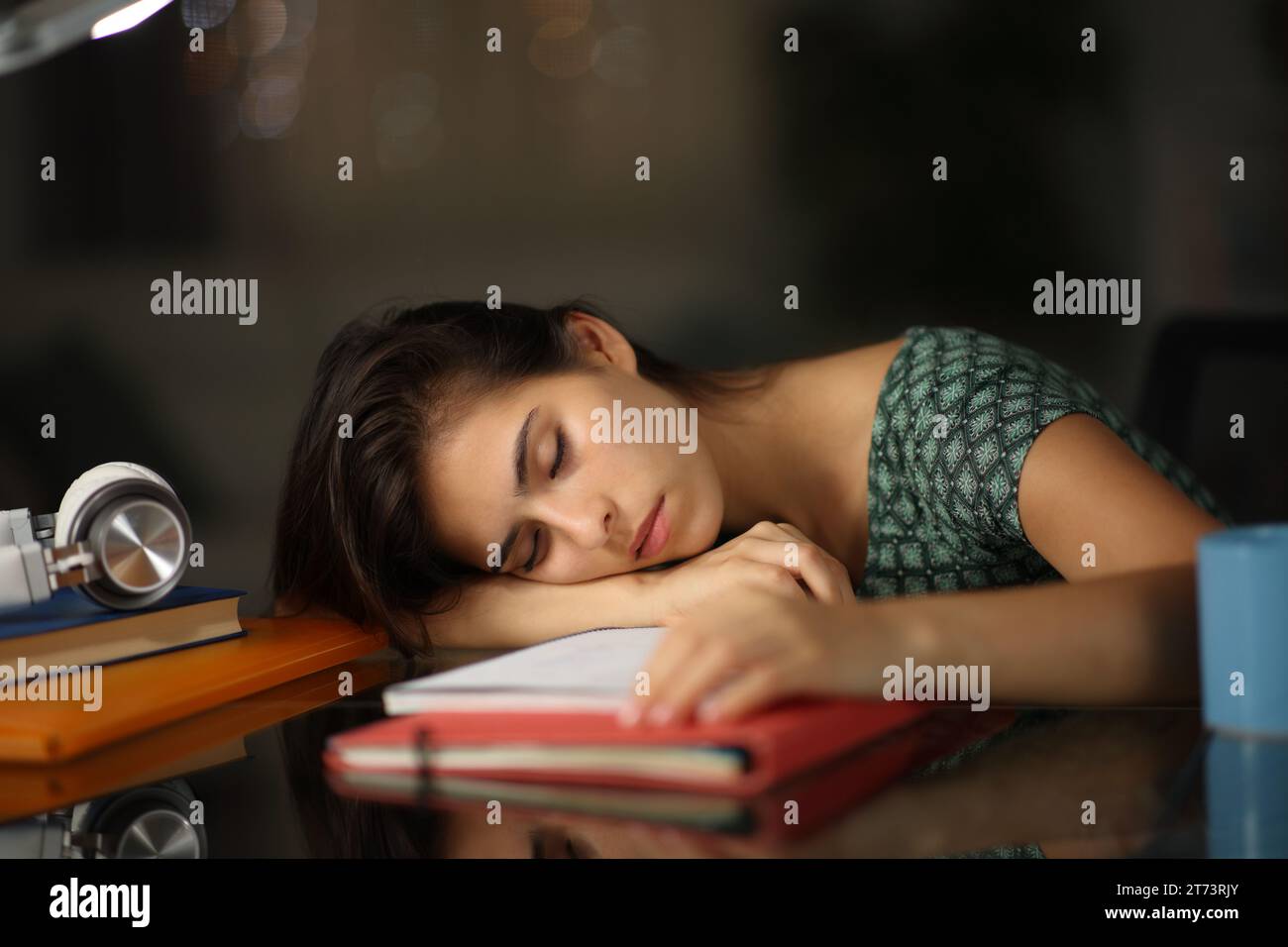Müder überarbeiteter Student, der nachts zu Hause über Notizen schläft Stockfoto