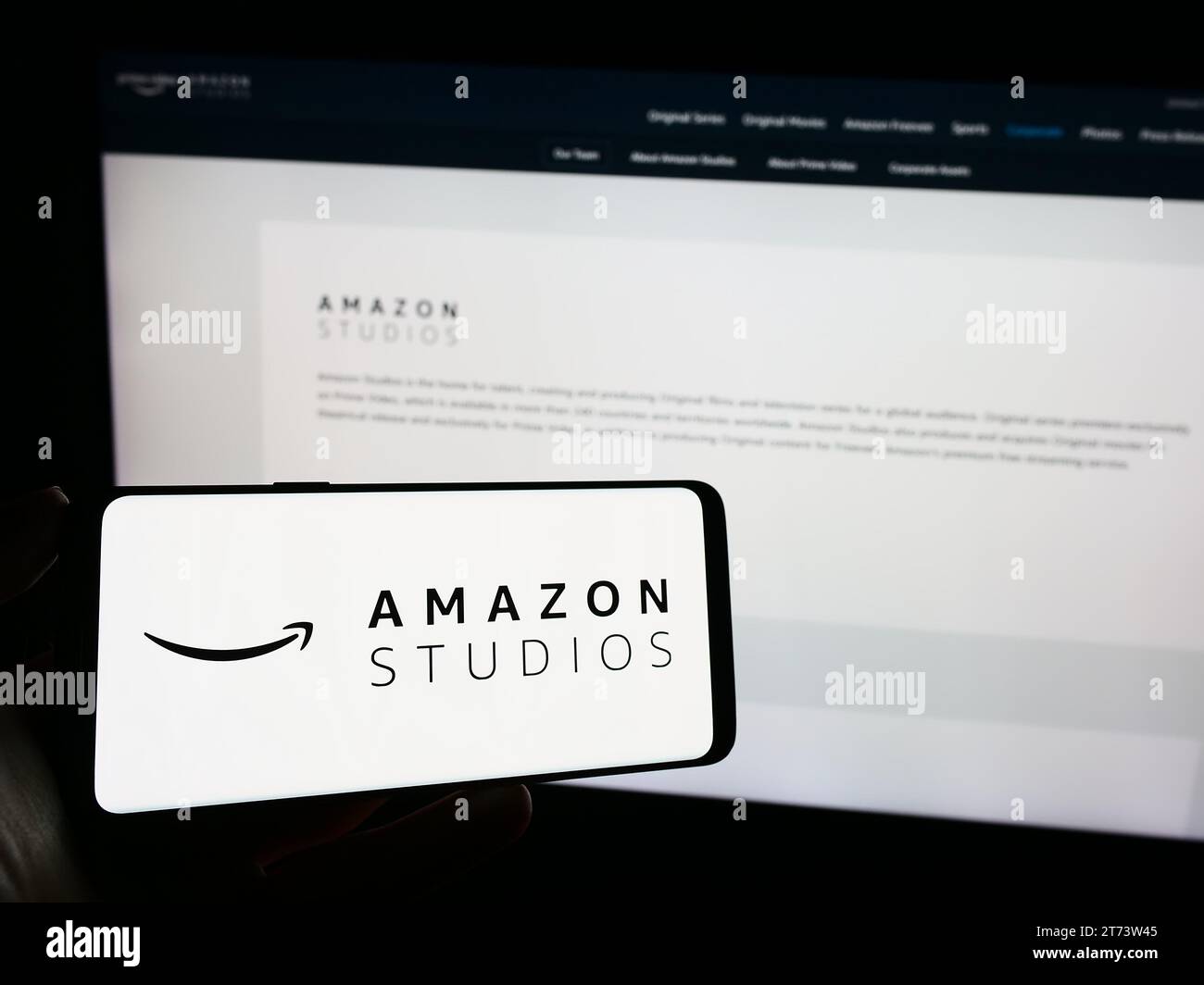Person mit Smartphone und Logo der US-amerikanischen Film- und Fernsehproduktionsfirma Amazon Studios vor der Website. Schwerpunkt auf dem Display des Telefons. Stockfoto